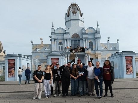 Die Reisegruppe mit 12 Personen steht vor dem Haupteingang des Freizeitparks
