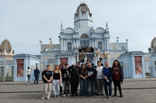 Die Reisegruppe mit 12 Personen steht vor dem Haupteingang des Freizeitparks